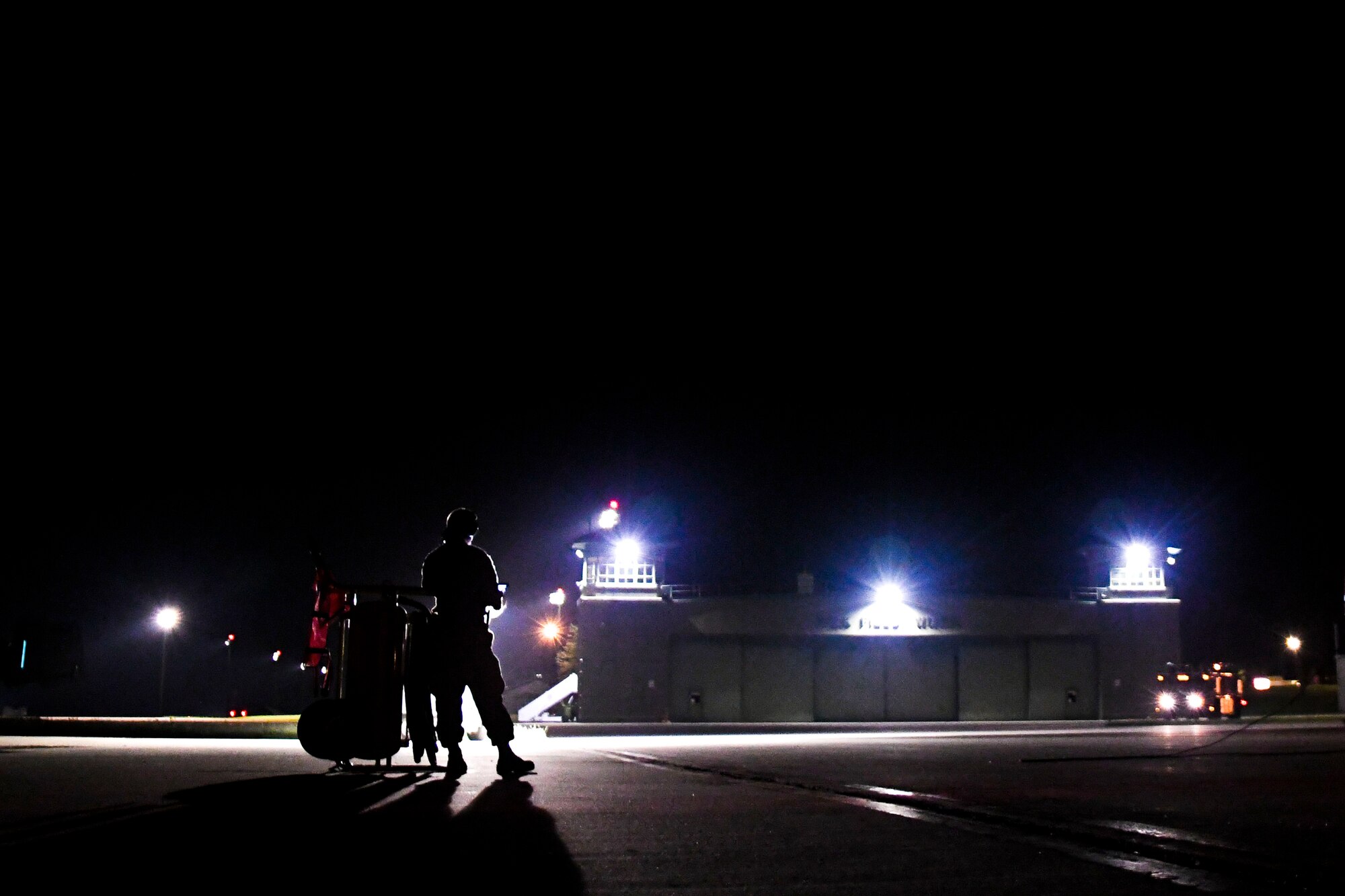 A photo of an airmen standing on the flight line at night