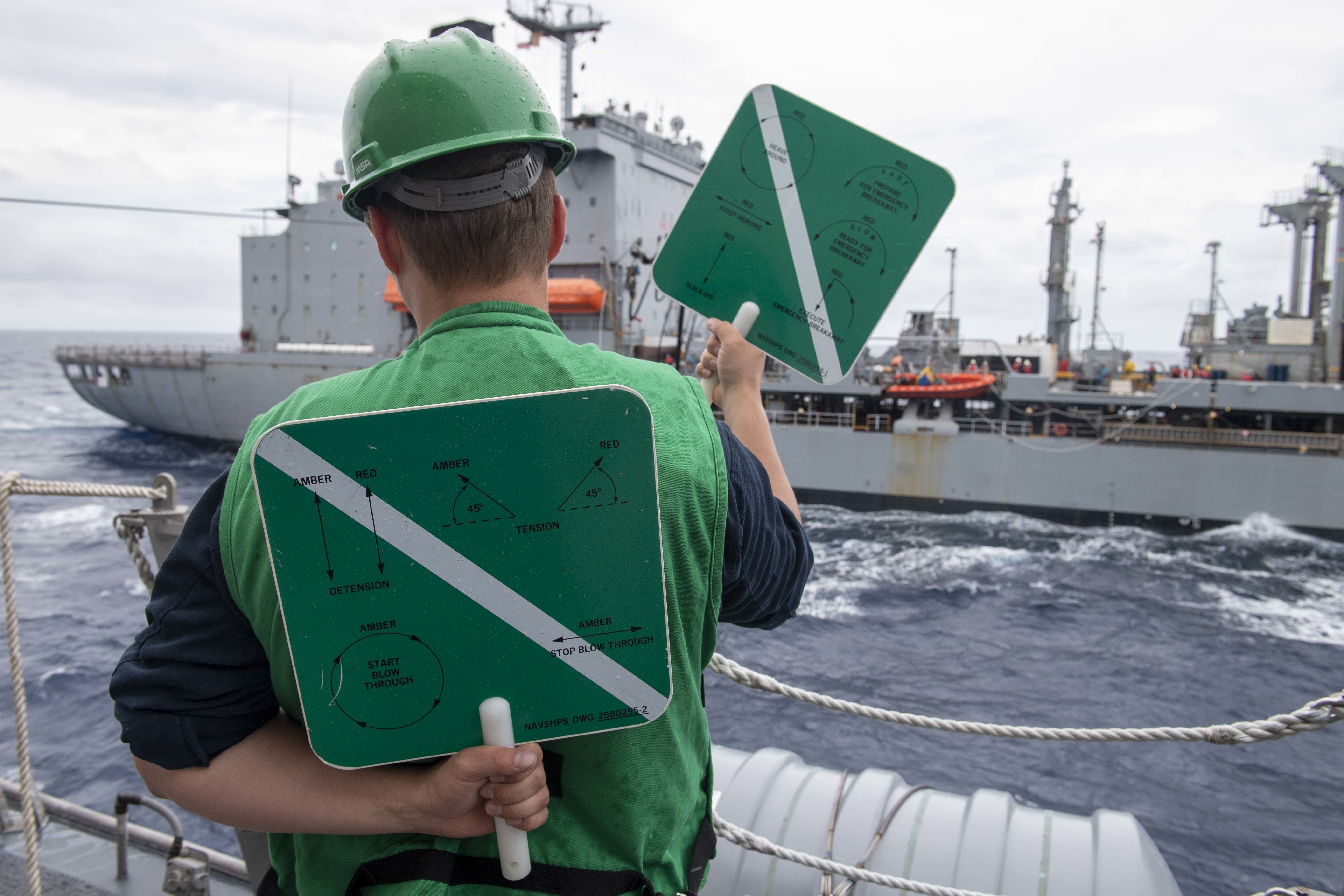 Mineman 3rd Class Hunter Auslander, from Fort Lauderdale, Fla., signals to heave around during a replenishment at sea aboard Independence-variant littoral combat ship USS Charleston (LCS 18) with Henry J. Kaiser-class underway replenishment oiler USNS Pecos (T-AO 197).