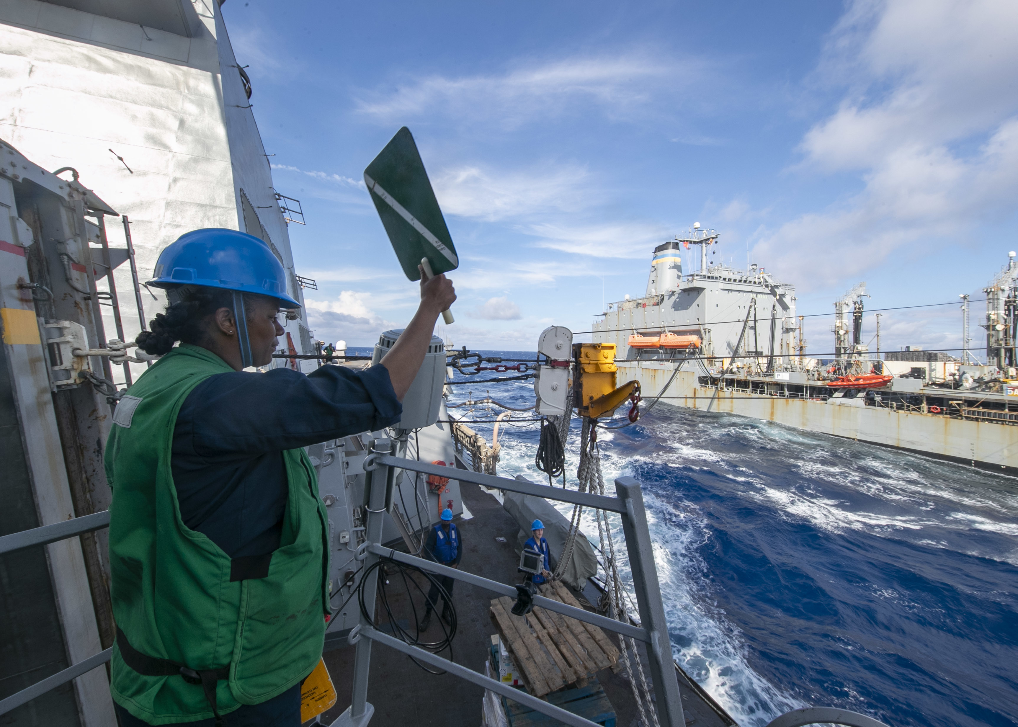 A Sailor assigned to the Arleigh Burke-class guided missile destroyer USS Lassen (DDG 82), signals USNS Joshua Humphreys (T-AO-188) during a replenishment-at-sea, June 12, 2021.