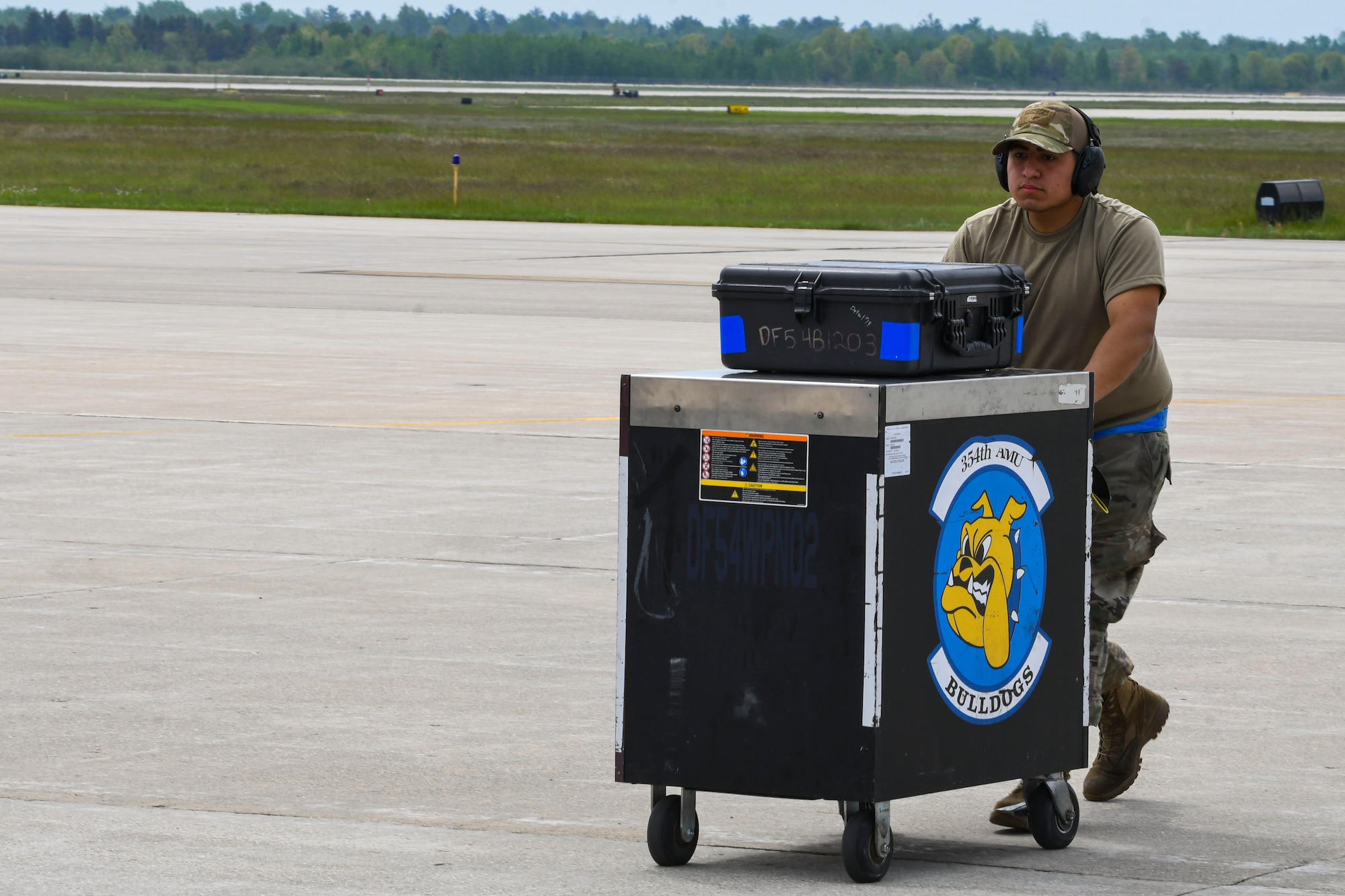 A photo of an airman pushing a tool box on a flight line