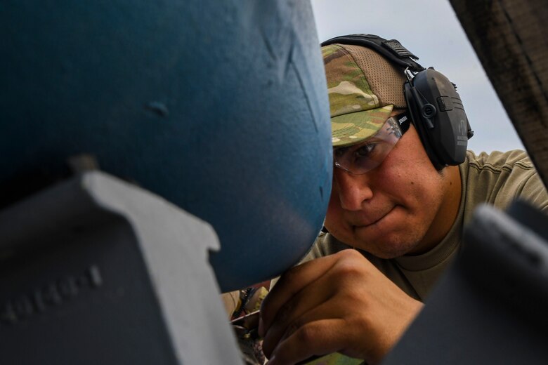 A photo of an airmen prepping munitions for loading