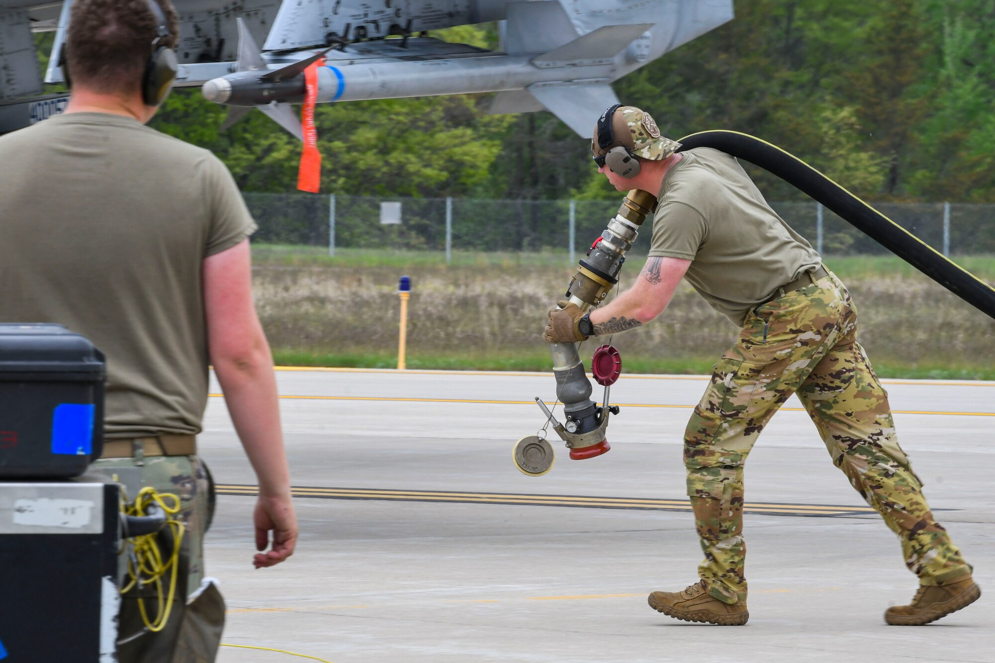 A photo of an airmen pulling a fueling nozzle