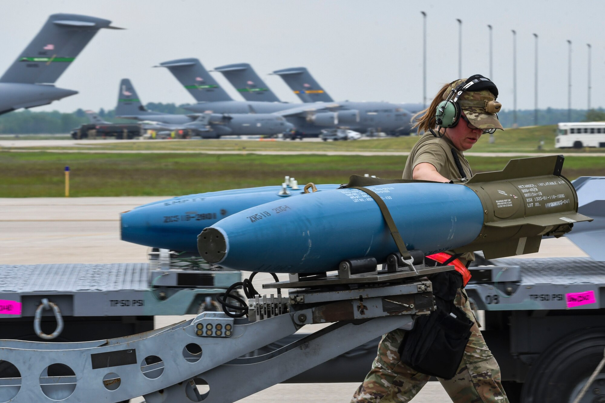 A photo of an airman guiding a munition to an airplane