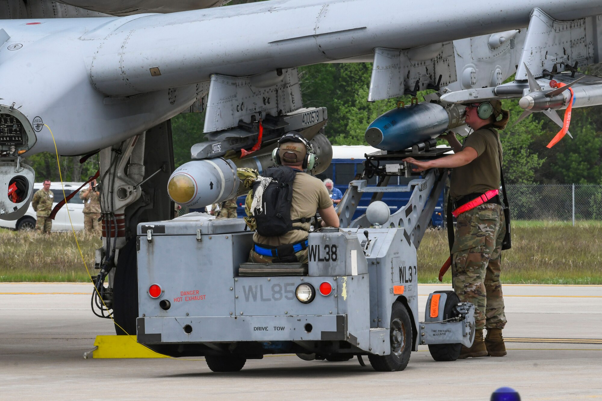 A photo of two airmen loading a munition to a plane
