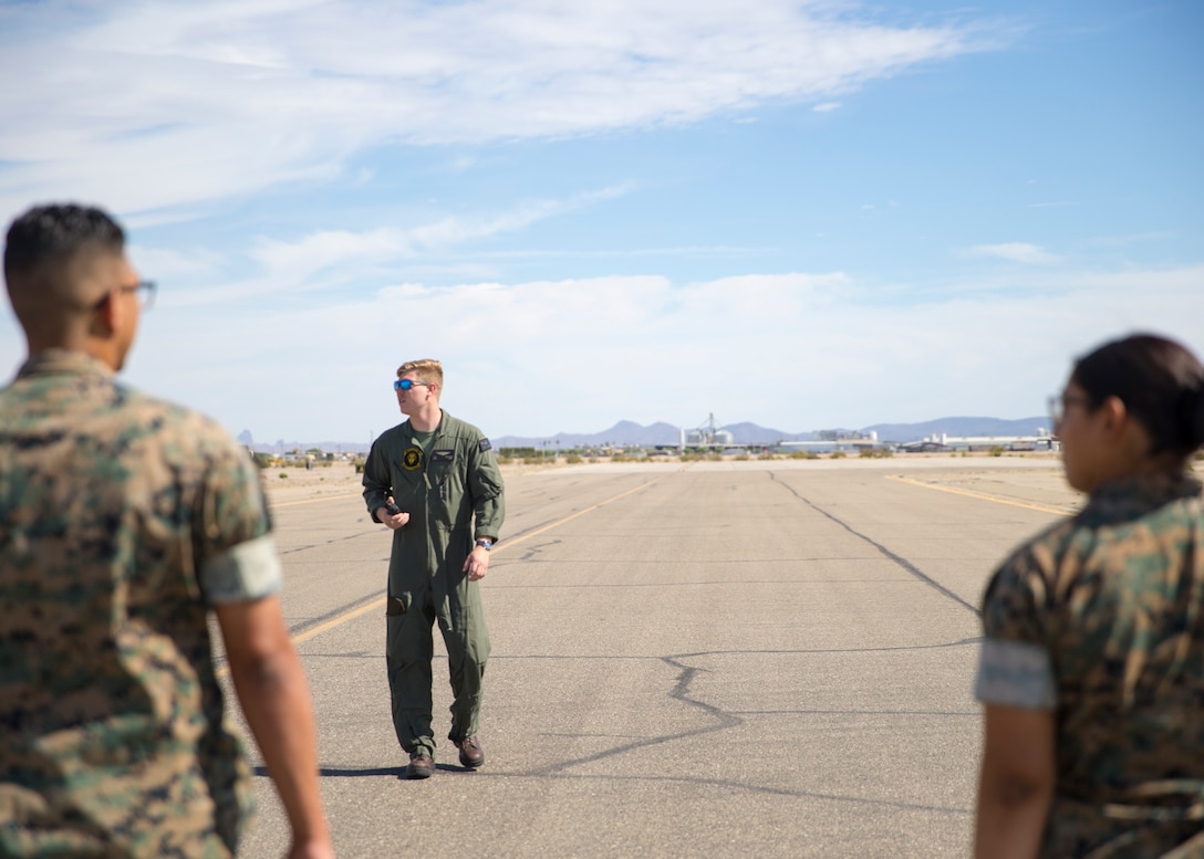 U.S. Marine Corps Cpl. Tyler Sullivan, a transport aircrewman with Headquarters and Headquarters Squadron, guides Marines during the Foreign Object Debris (FOD) walk at Marine Corps Air Station Yuma, Ariz.,  June 7, 2021.