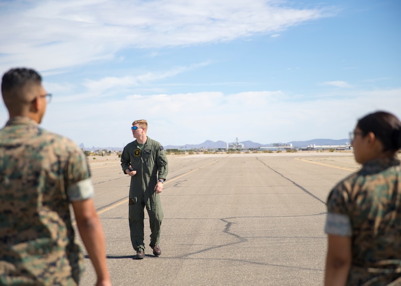 U.S. Marine Corps Cpl. Tyler Sullivan, a transport aircrewman with Headquarters and Headquarters Squadron, guides Marines during the Foreign Object Debris (FOD) walk at Marine Corps Air Station Yuma, Ariz.,  June 7, 2021. A FOD walk is conducted routinely to make sure runways are clear from debris that may damage aircraft using it. (U.S. Marine Corps Photo by Lance Cpl Matthew Romonoyske-Bean)