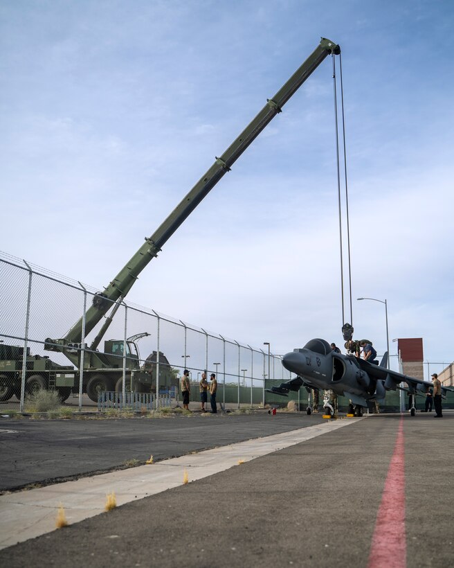 An AV-8B Harrier jet is lifted over a gate on Marine Corps Air Station Yuma, June 7, 2021. The Harrier is now a static display near the entrance of the Air Station. (U.S. Marine Corps photo by Lance Cpl. Carlos Kealy)