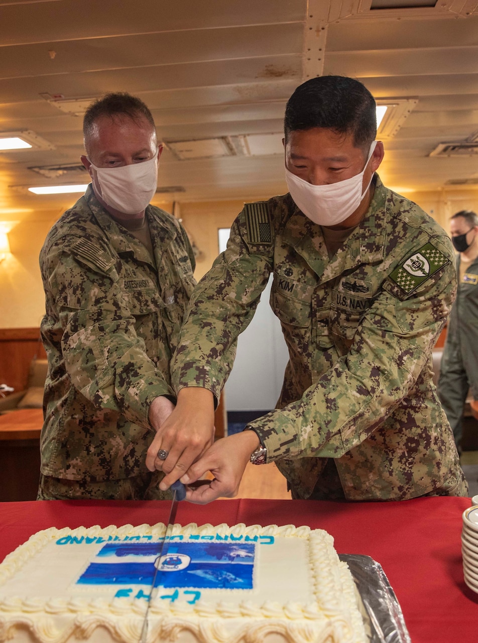 NAVAL BASE GUAM (April 20, 2021) – U.S. Navy Capt. Henry Kim, right, cuts a cake with Capt. Stewart Bateshansky aboard the amphibious assault ship USS Makin Island (LHD 8) following a ceremony where Kim relieved Bateshanksy as commander of Amphibious Squadron THREE. The Makin Island Amphibious Ready Group and the 15th Marine Expeditionary Unit are operating in the U.S. 7th Fleet area of operations as part of a scheduled deployment to the region. As the U.S. Navy’s largest forward-deployed fleet, 7th Fleet routinely operates and interacts with 35 maritime nations while conducting missions to preserve and protect a free and open Indo-Pacific Region. (U.S. Navy photo by Mass Communication Specialist 2nd Class Michael J. Lieberknecht)