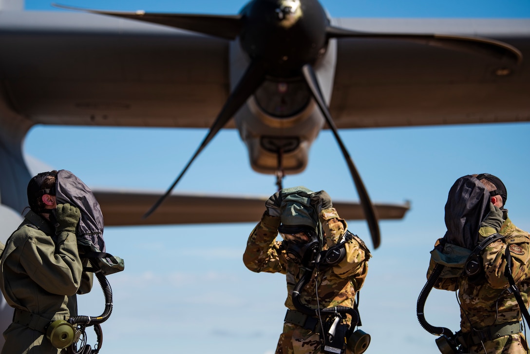 First Lt. Coltan Nading, 40th Airlift Squadron pilot, left, Capt. Miranda Mila, 40th AS pilot, center, and Senior Airman Noah Isom, 39th AS loadmaster, remove their gas masks next to a C-130J Super Hercules at Dyess Air Force Base, Texas, June 2, 2021. The aircrew demonstrated the operability of the new Uniform Integrated Protective Ensemble Air 2 Piece Under Garment chemical protective suit during simulated preflight and ground egress procedures.