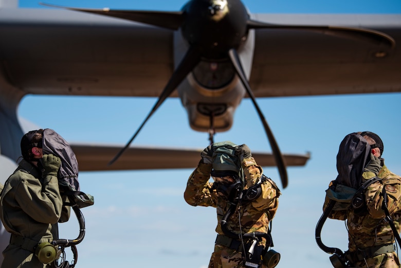 First Lt. Coltan Nading, 40th Airlift Squadron pilot, left, Capt. Miranda Mila, 40th AS pilot, center, and Senior Airman Noah Isom, 39th AS loadmaster, remove their gas masks next to a C-130J Super Hercules at Dyess Air Force Base, Texas, June 2, 2021. The aircrew demonstrated the operability of the new Uniform Integrated Protective Ensemble Air 2 Piece Under Garment chemical protective suit during simulated preflight and ground egress procedures.