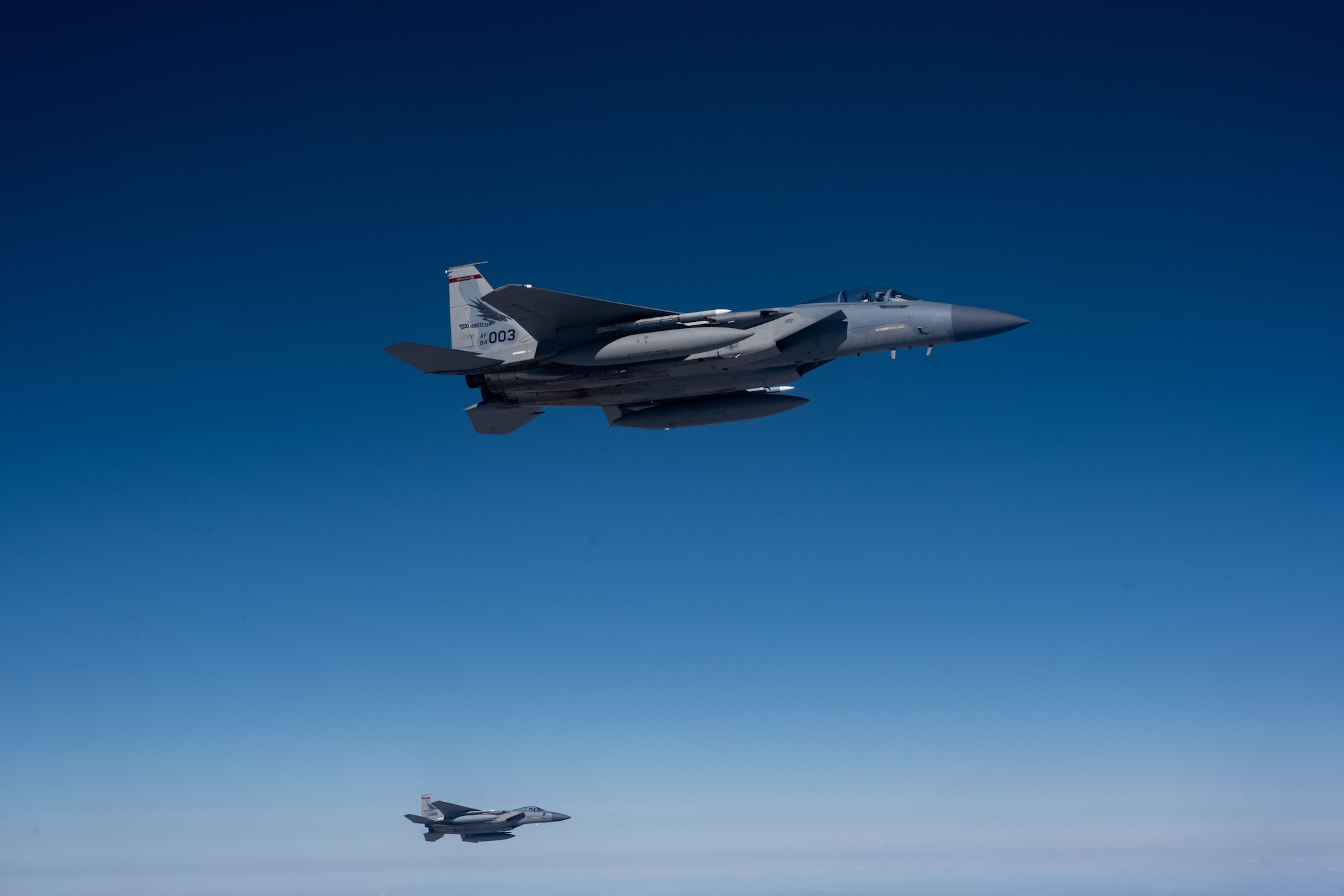 Two F-15 jet aircrafts is flying high in the sky.