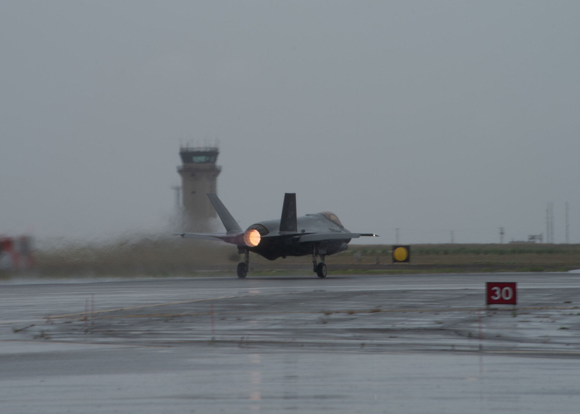 A F-35 jet aircraft speeds up in order to fly off the flight line runway.