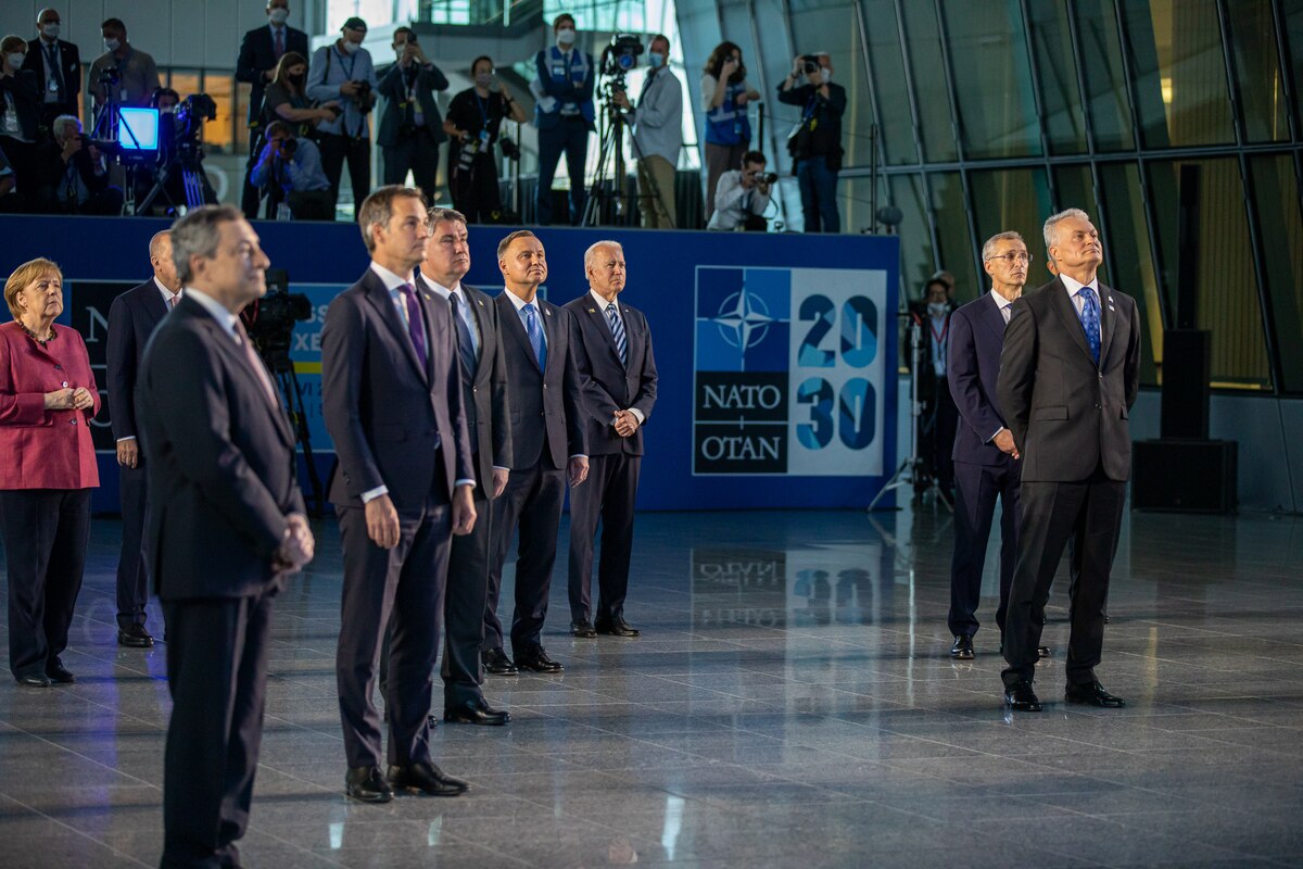 Internations leaders stand watching a presentation.