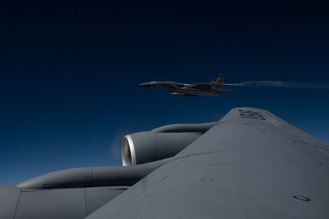 A F-15C jet flies next to KC-135 Startotanker.