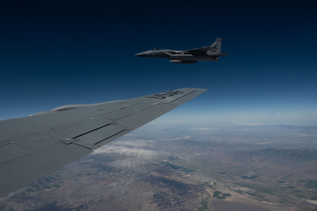 A F-15 jet aircraft flies next to KC-135 Stratotanker.