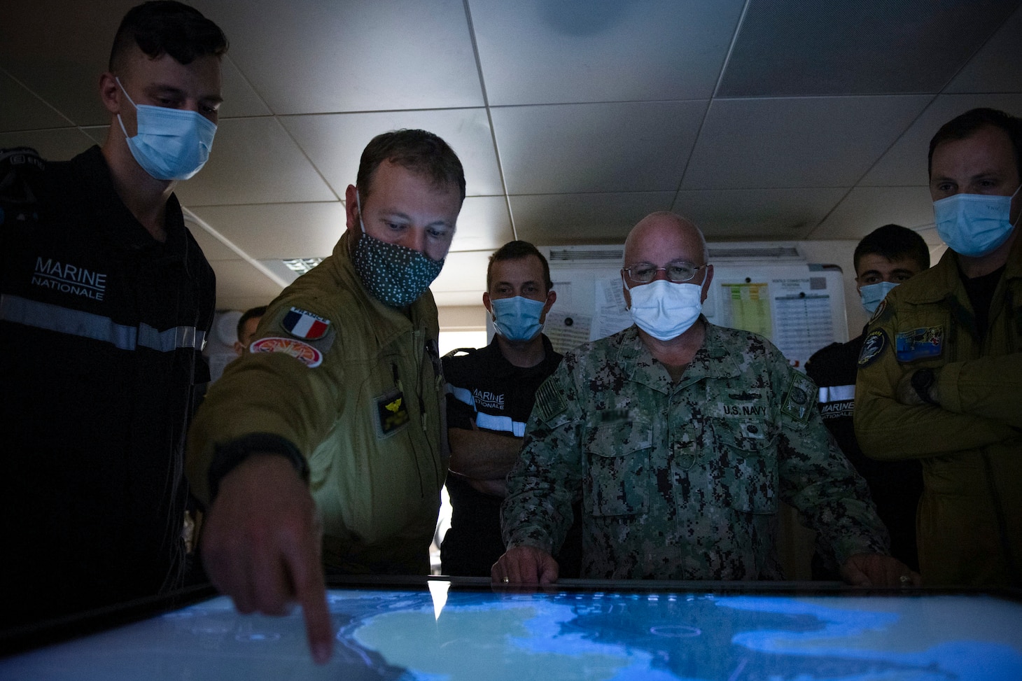 U.S. 7th Fleet's Enforcement Coordination Cell (ECC) director, Capt. James J. Mehail, observes a helicopter mission in the combat information center from Cmdr. Nicolas Fredon, the French Navy liasion officer for ECC. As the U.S. Navy's largest forward-deployed fleet, 7th Fleet employs 50-70 ships and submarines across the Western Pacific and Indian oceans. U.S. 7th Fleet routinely operates and interacts with 35 maritime nations while conducting missions to preserve and protect a free and open Indo-Pacific Region.