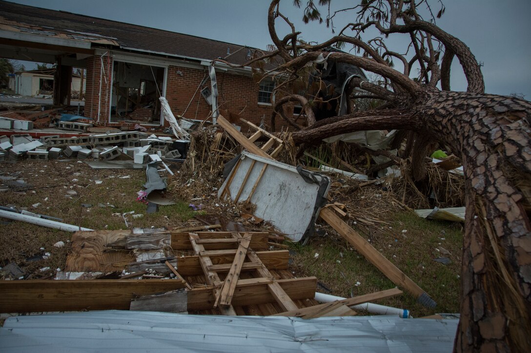 Debris fills a yard in front of a house.