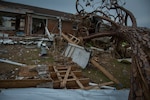 Debris fills a yard in front of a house.