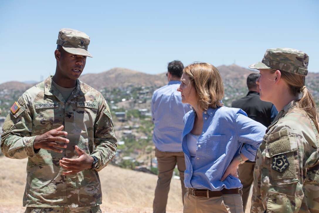 Deputy Defense Secretary Dr. Kathleen H. Hicks talks with a service member at an outdoor site.