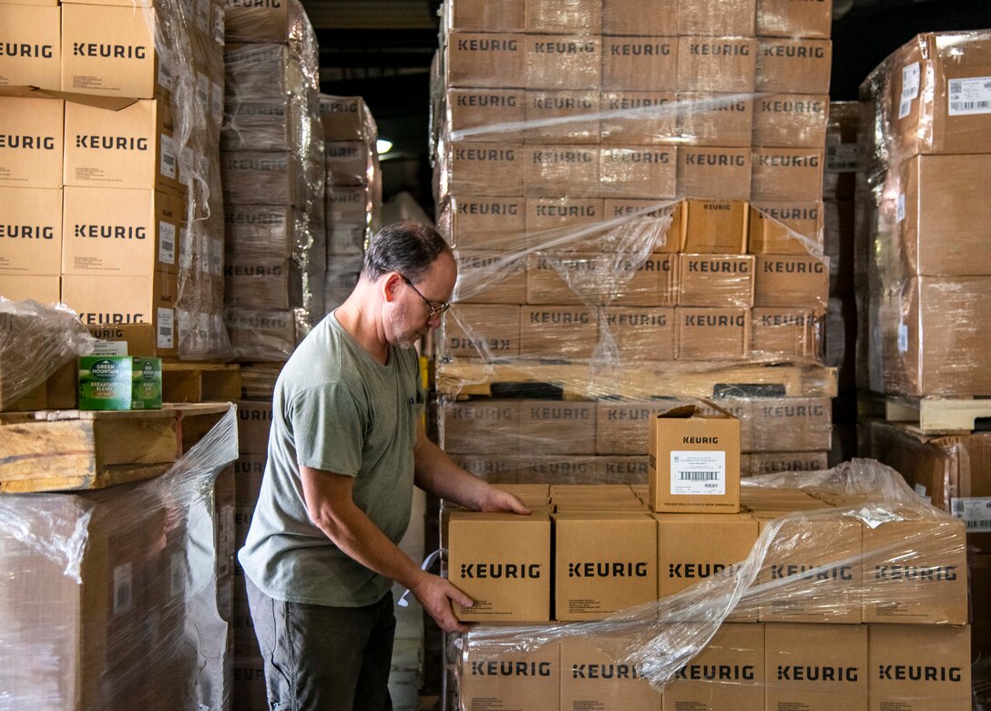 Patrick Brady, 436th Aerial Port Squadron traffic management woodworker, sorts through pallets of donated coffee by Holy Joe’s Café at Dover Air Force Base, Delaware, June 10, 2021. Holy Joe’s Café has sent free coffee to U.S. military bases since 2006. They work with military chaplains to provide thousands of free cups of coffee to troops in 70 countries throughout the world. (U.S. Air Force photo by Airman 1st Class Stephani Barge)