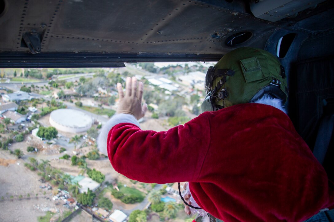 U.S. Marine Sgt. William Hinkle, an aerial observer with Marine Light Attack Helicopter Training Squadron 303, Marine Aircraft Group 39, 3rd Marine Aircraft Wing, waves to families while dressed as Santa Claus as he flies over a neighborhood outside of Marine Corps Base Camp Pendleton, California, in a UH-1Y Venom helicopter, Dec. 5, 2020. Since efforts to mitigate the spread of COVID-19 have impacted holiday plans for many living in Southern California, HMLAT-303 wanted to bring Santa Claus to families living on base and the surrounding area to spread holiday cheer. Hinkle is a native of Parachute, Colorado. (U.S. Marine Corps photo by Lance Cpl. Drake Nickels)