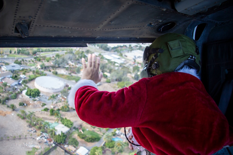 U.S. Marine Sgt. William Hinkle, an aerial observer with Marine Light Attack Helicopter Training Squadron 303, Marine Aircraft Group 39, 3rd Marine Aircraft Wing, waves to families while dressed as Santa Claus as he flies over a neighborhood outside of Marine Corps Base Camp Pendleton, California, in a UH-1Y Venom helicopter, Dec. 5, 2020. Since efforts to mitigate the spread of COVID-19 have impacted holiday plans for many living in Southern California, HMLAT-303 wanted to bring Santa Claus to families living on base and the surrounding area to spread holiday cheer. Hinkle is a native of Parachute, Colorado. (U.S. Marine Corps photo by Lance Cpl. Drake Nickels)