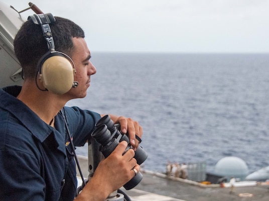 Seaman Carlos Diaz, from Minneapolis, Minnesota stands port watch on the bridge wing of the U.S. Navy's only forward-deployed aircraft carrier USS Ronald Reagan (CVN 76).