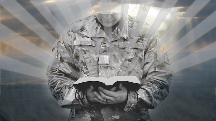 Picture of servicemember holding a book that has rays of sunshine extending out from it.