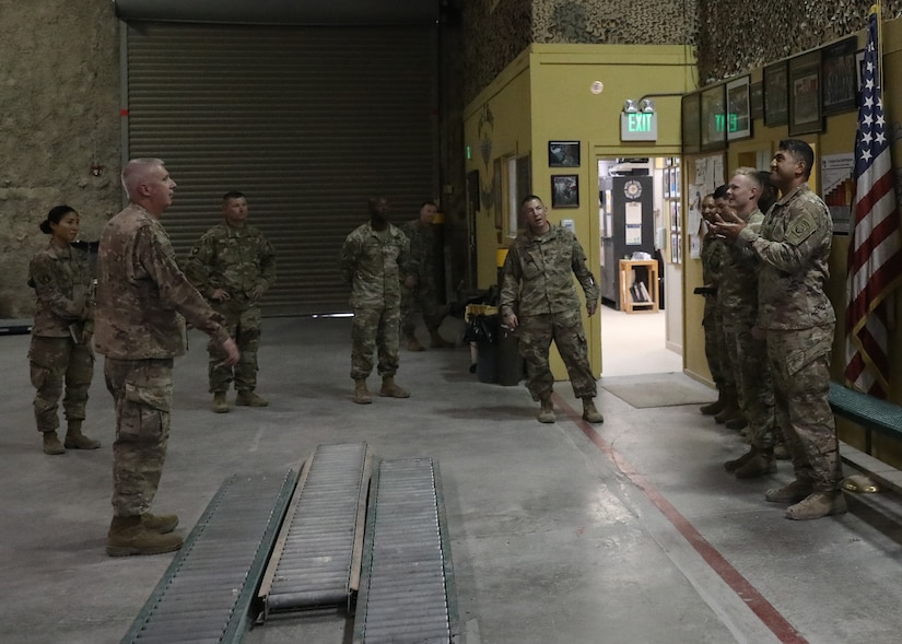 Due to social distancing, Commanding General of 1st Theater Sustainment Command, Maj. Gen. John P. Sullivan, tosses command coins to Spc. Paulo Paulo and Sgt. Joshua Parkinson, of the Fort Bragg, N.C., based 151st Quartermaster Detachment. The two Soldiers were coined by the general during his June 10, 2021 visit to the Eric T. Burri, U.S. Army Rigging Facility at Al Udeid Air Base, Qatar. The riggers deployed to Qatar in support of 1st TSC's logistics mission and military operations in the U.S. Central Command area of responsibility.