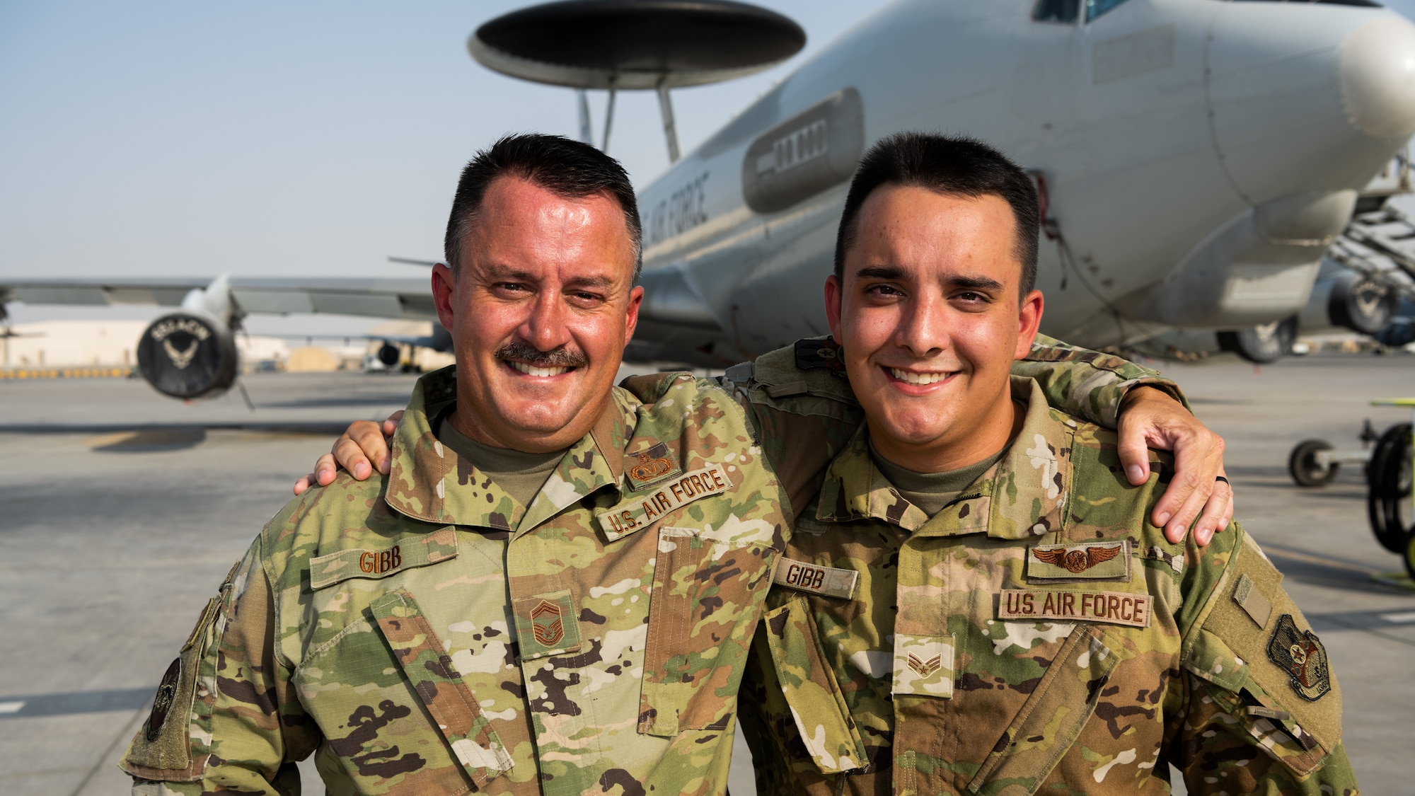 U.S. Air Force Senior Master Sgt. Daniel Gibb, 968th Expeditionary Airborne Air Control Squadron (EAACS) aviation resource manager, and his son Senior Airman Derek Gibb, 968th EAACS computer display maintenance technician, pose for a photo in front of their unit’s E-3 Sentry aircraft at Al Dhafra Air Base, United Arab Emirates, May 26, 2021. Both father and son are first time deployers.