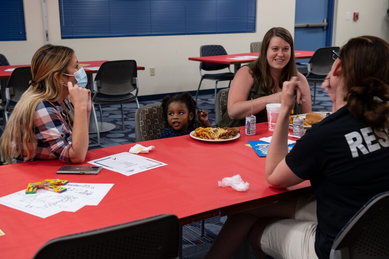 A photo of a family talking with volunteers over dinner.