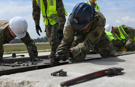 Michigan Air National Guard power production Airmen from the 110th Civil Engineer Squadron and the Alpena Combat Readiness Training Center remove a fairlead beam June 8, 2021. They replaced the aircraft arresting system, which helps stop aircraft with tailhooks in case of emergency.