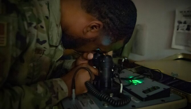 An Airman stands in front of night vision goggles.