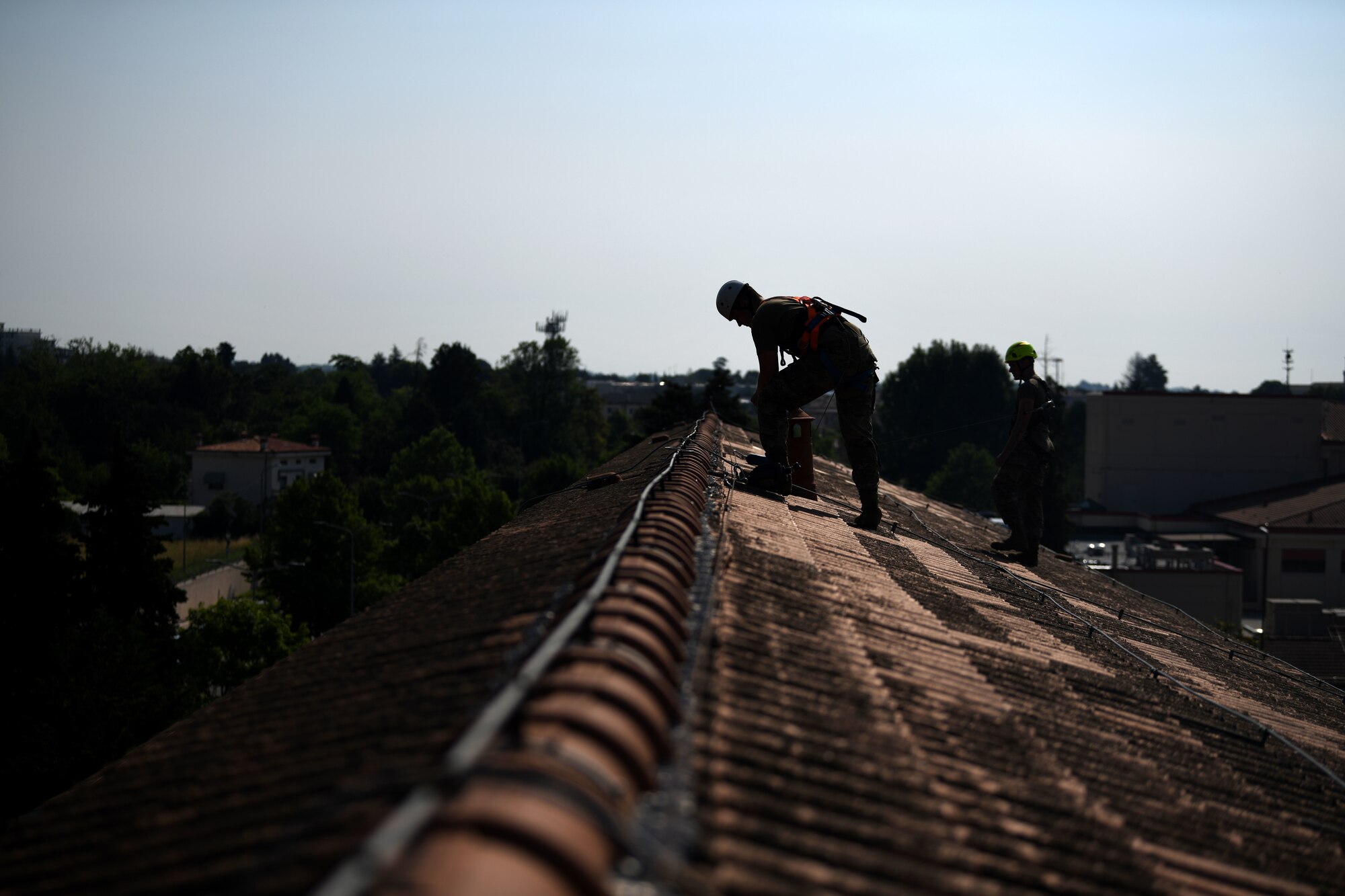 Senior Airman Tyler J. Vance, 31st Civil Engineer Squadron (CES) structural journeyman, left, and Airman Bryce E. Schneider, 31st CES structural apprentice, conduct preventative maintenance on a roof  
at Aviano Air Base, Italy, June 17, 2021. Airmen from the 31st CES complete preventative maintenance on roofs quarterly, semiannually, and annually. (U.S. Air Force photo by Senior Airman Ericka A. Woolever)