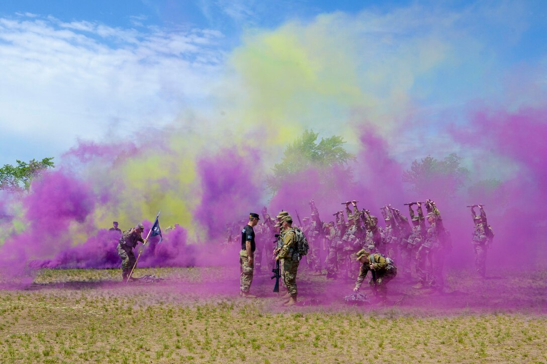 Soldiers stand in a group surrounded by purple and yellow smoke.