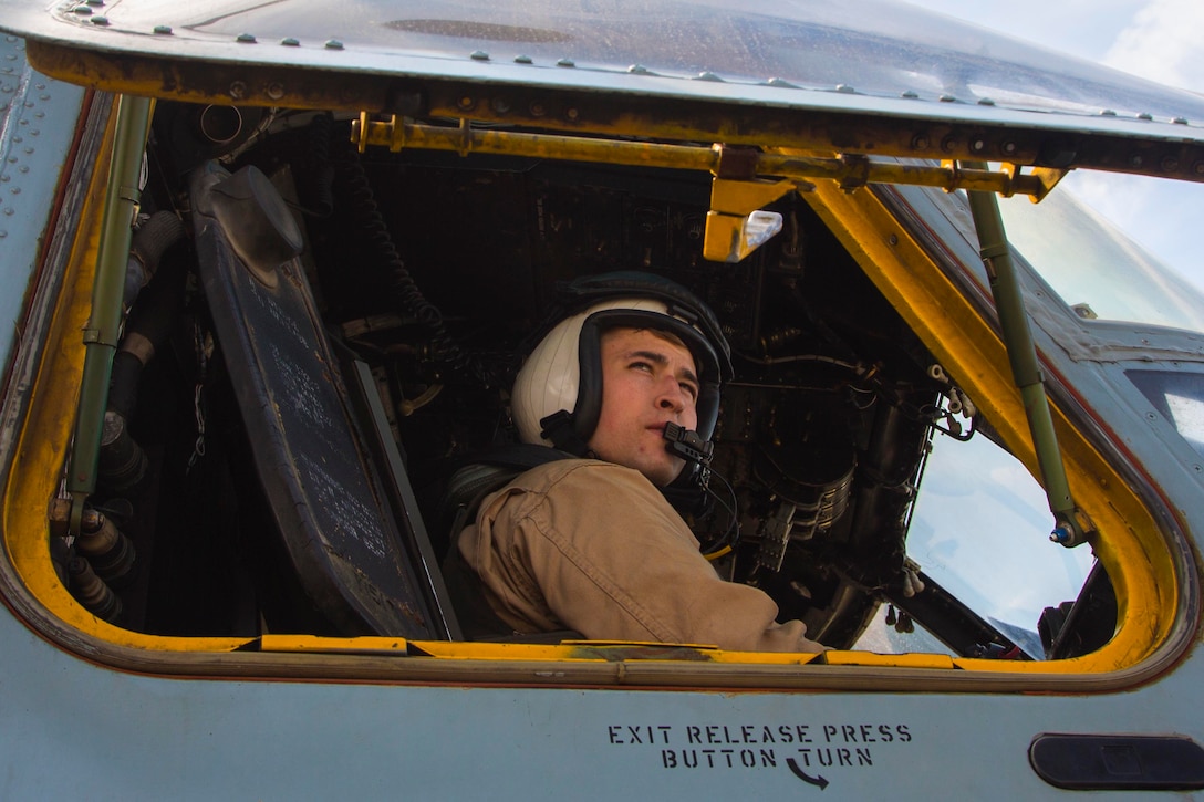 A Marine sits in the cockpit of an aircraft.