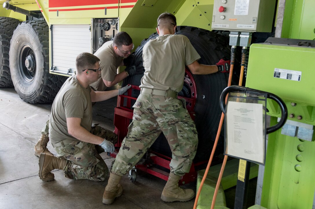 Steven Spitzer and Staff Sgt. Dallas Nichols, vehicle maintainers with the 167th Logistics Readiness Squadron, place a wheel and tire on a firetruck using mounting equipment as part of vehicle maintenance at the 167th Airlift Wing, Martinsburg, West Virginia, June 10, 2021. The wheels and tires from one truck were swapped with those of another to maintain tread life