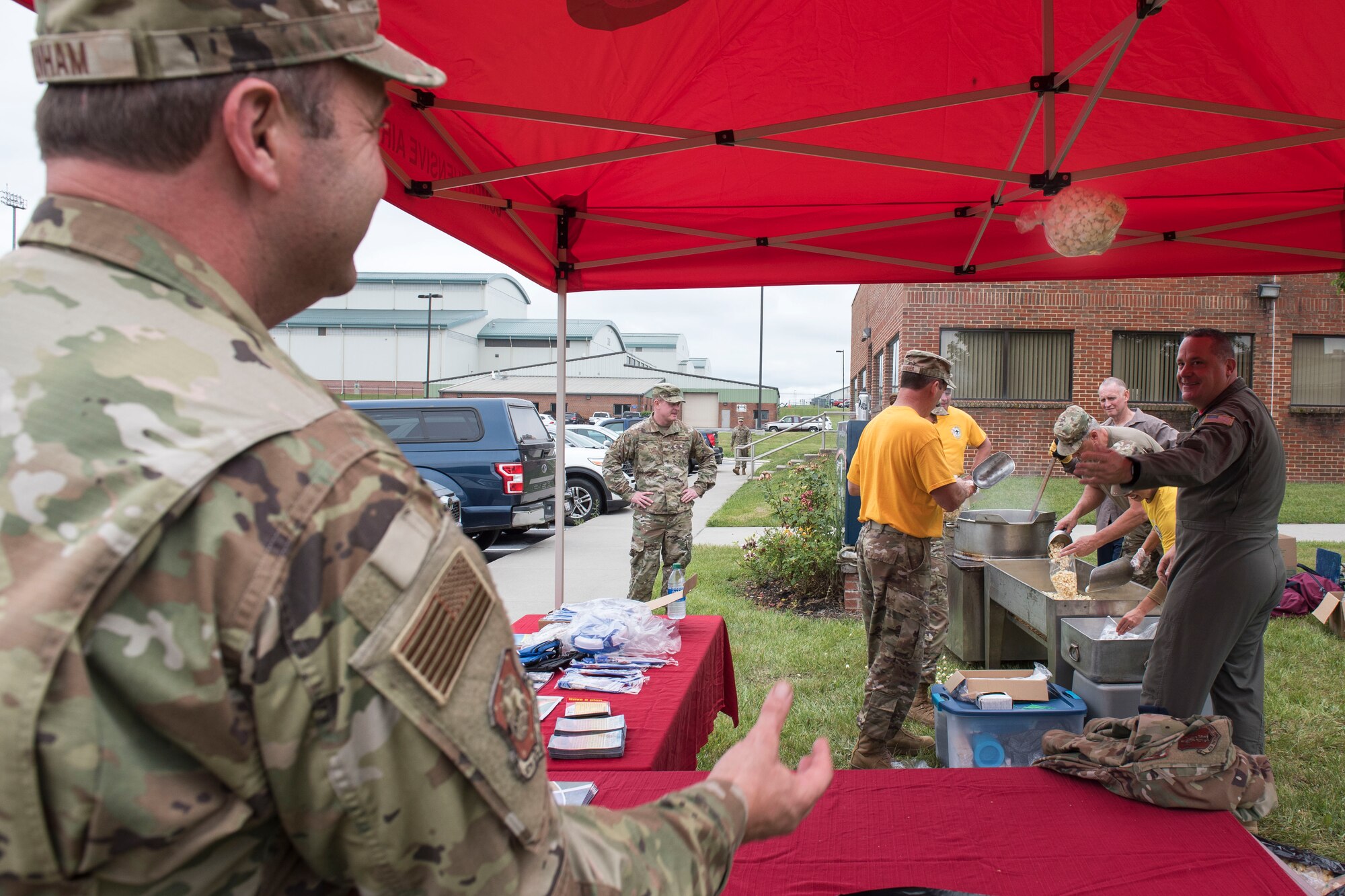 U.S. Air Force Chief Master Sgt. Mark Snyder, right, 167th Airlift Wing loadmaster, tosses a bag of kettle corn to Capt. Clinton Dunham, a 167th personnel officer assigned to the equal opportunity office, who was manning a wellness resources tent as part of the wing’s unit training assembly activities at Shepherd Field, Martinsburg, West Virginia, June 12, 2021. The 167th AW Chiefs’ Council prepared the kettle corn that was handed out by the Wing Care Team at a tent set up in front of the wing dining facility to help make Airmen aware of the wellness resources available to them.