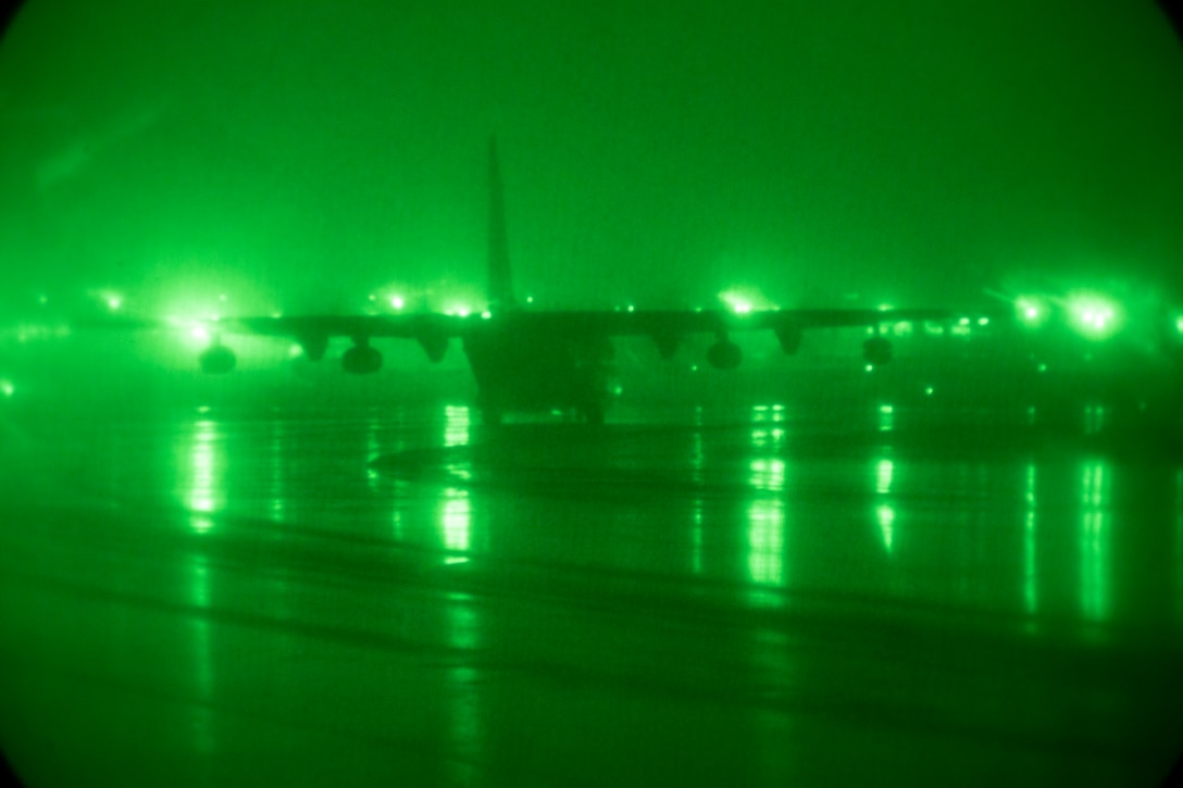 An aircraft moves on a tarmac illuminated by green light.