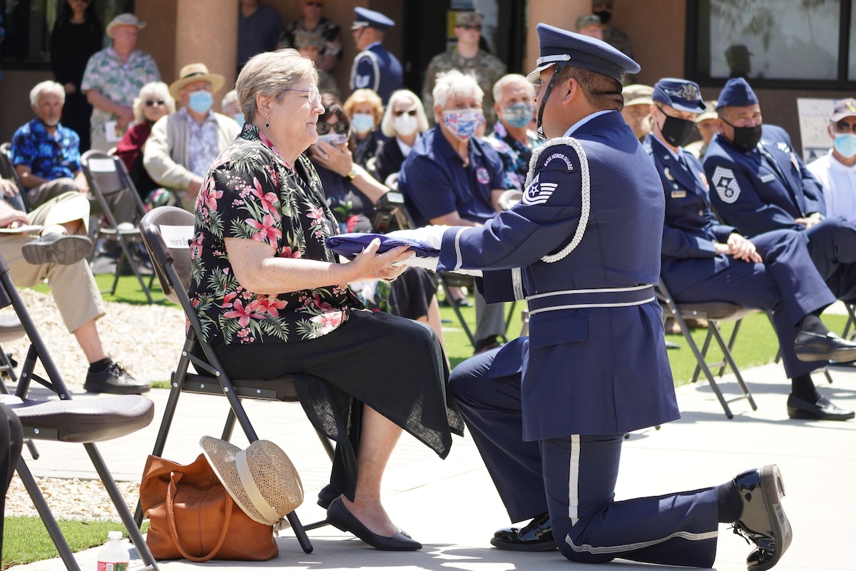 A U.S. Air National Guard Honor Guard member hands a widow a flag.