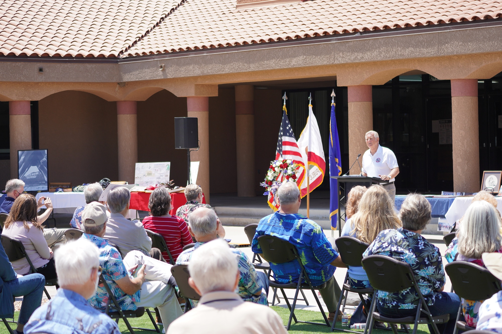 A picture of an alumni guest speaker talking to an audience at a celebration of life inside the heritage square plaza at Channel Islands Air National Guard Station.