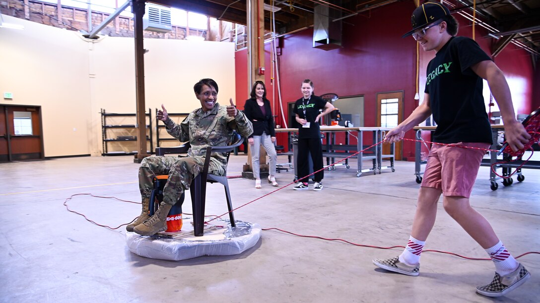 Connor Robinson, a LEGACY program student, pulls Col. Jenise Carroll, 75th Air Base Wing commander, on a hoverboard students built during a summer camp in Clearfield, Utah, June 11, 2021. The Leadership Experience Growing Apprenticeships Commited to Youth, or LECAGY program, provides a STEM pipeline that starts with students at age 11 and keeps them in the program until college graduation. (U.S. Air Force photo by R. Nial Bradshaw)