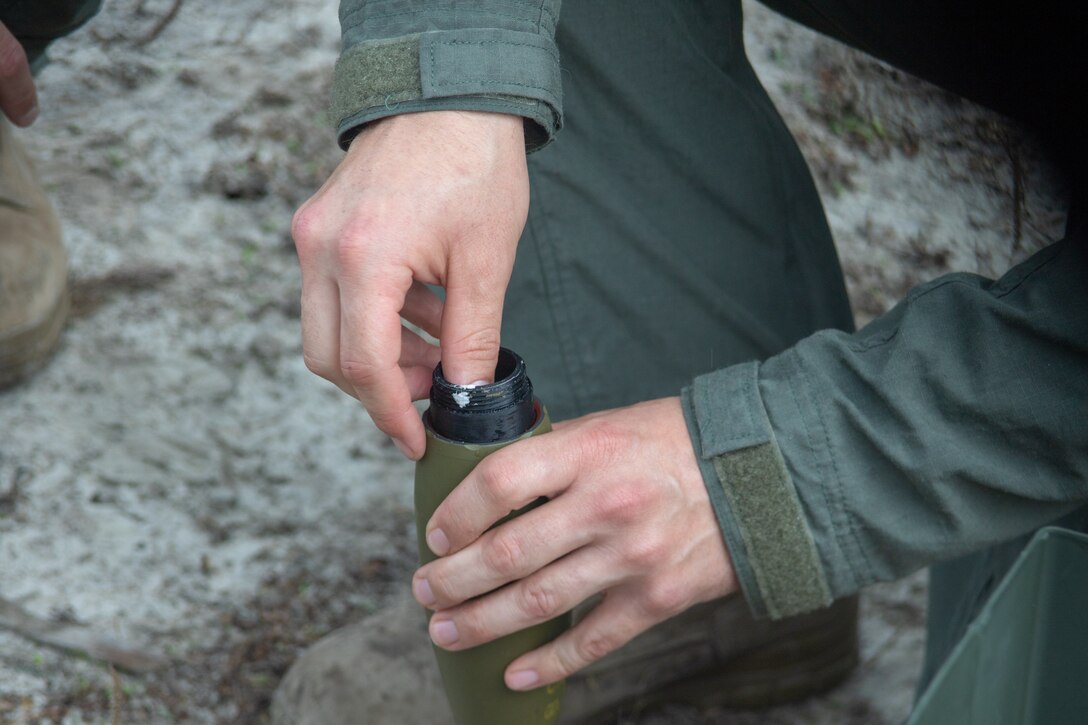 An Explosive Ordnance Disposal technician with Headquarters and Headquarters Squadron packs a mortar with C-4 at Marine Corps Air Station Cherry Point, North Carolina, June 9, 2021. The mortars were placed in front of man-shaped targets and detonated to demonstrate to Carteret County Special Response Teams the effect of an actual mortar going off. (U.S. Marine Corps Photo by Lance Cpl. Symira Bostic)