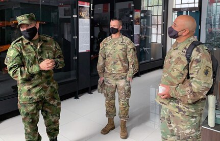 Three men in military uniform stand in hallway