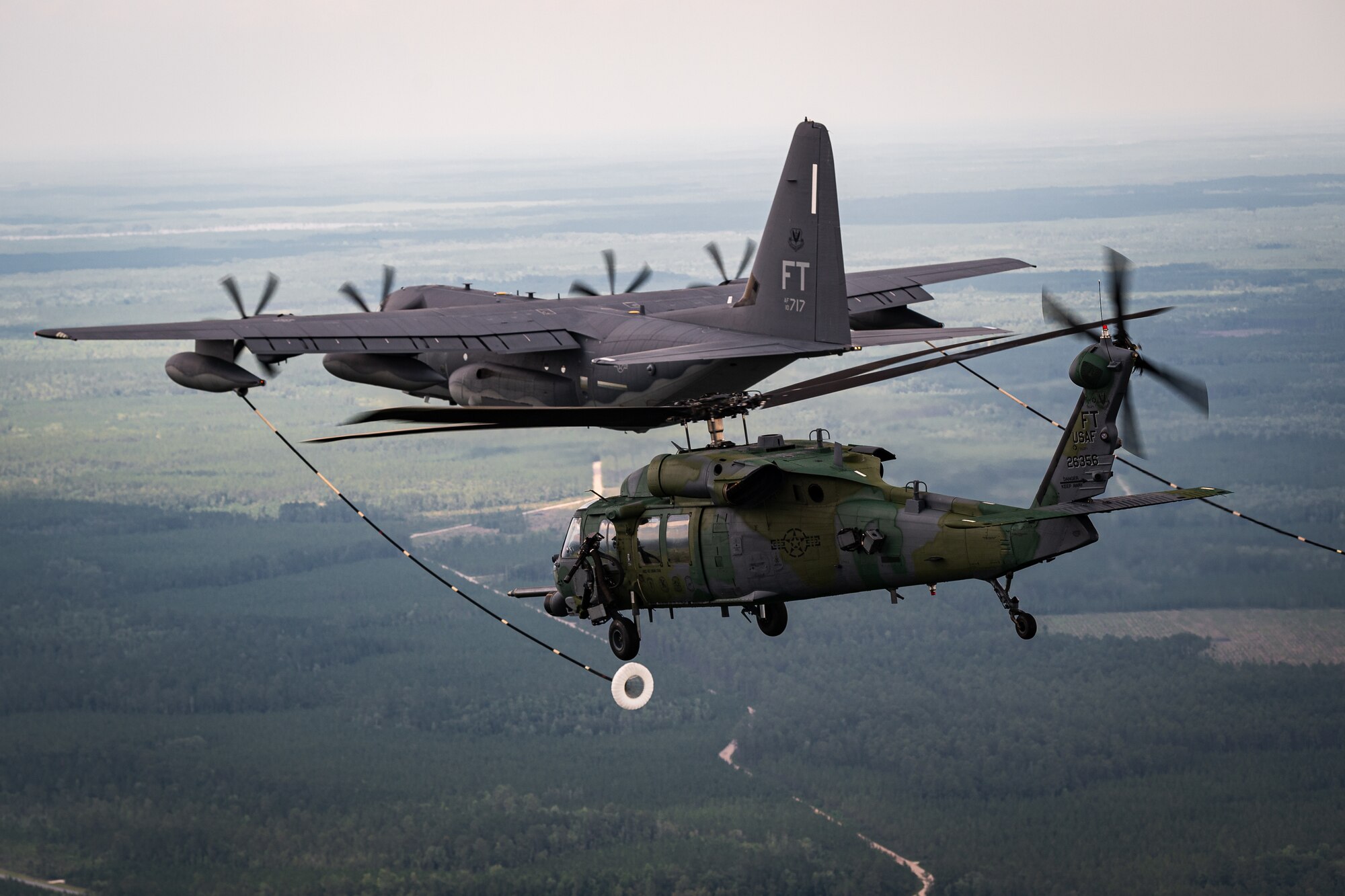 A helicopter receives fuel from C-130