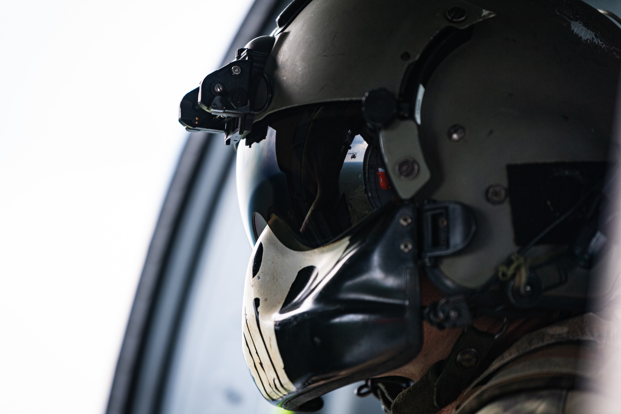 An aviator looks out of a helicopter in flight