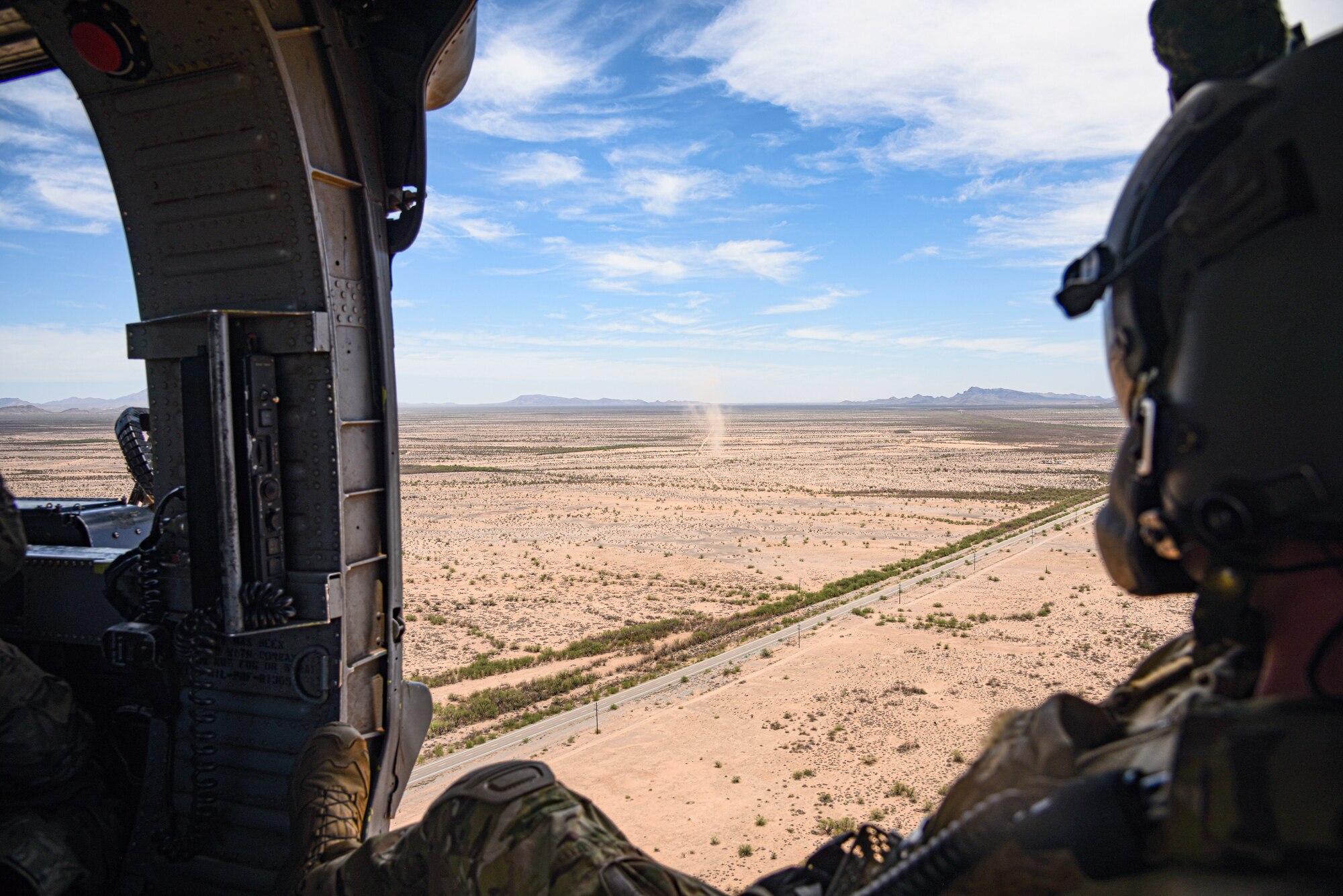 A photo of an airmen looking out the door of a helicopter