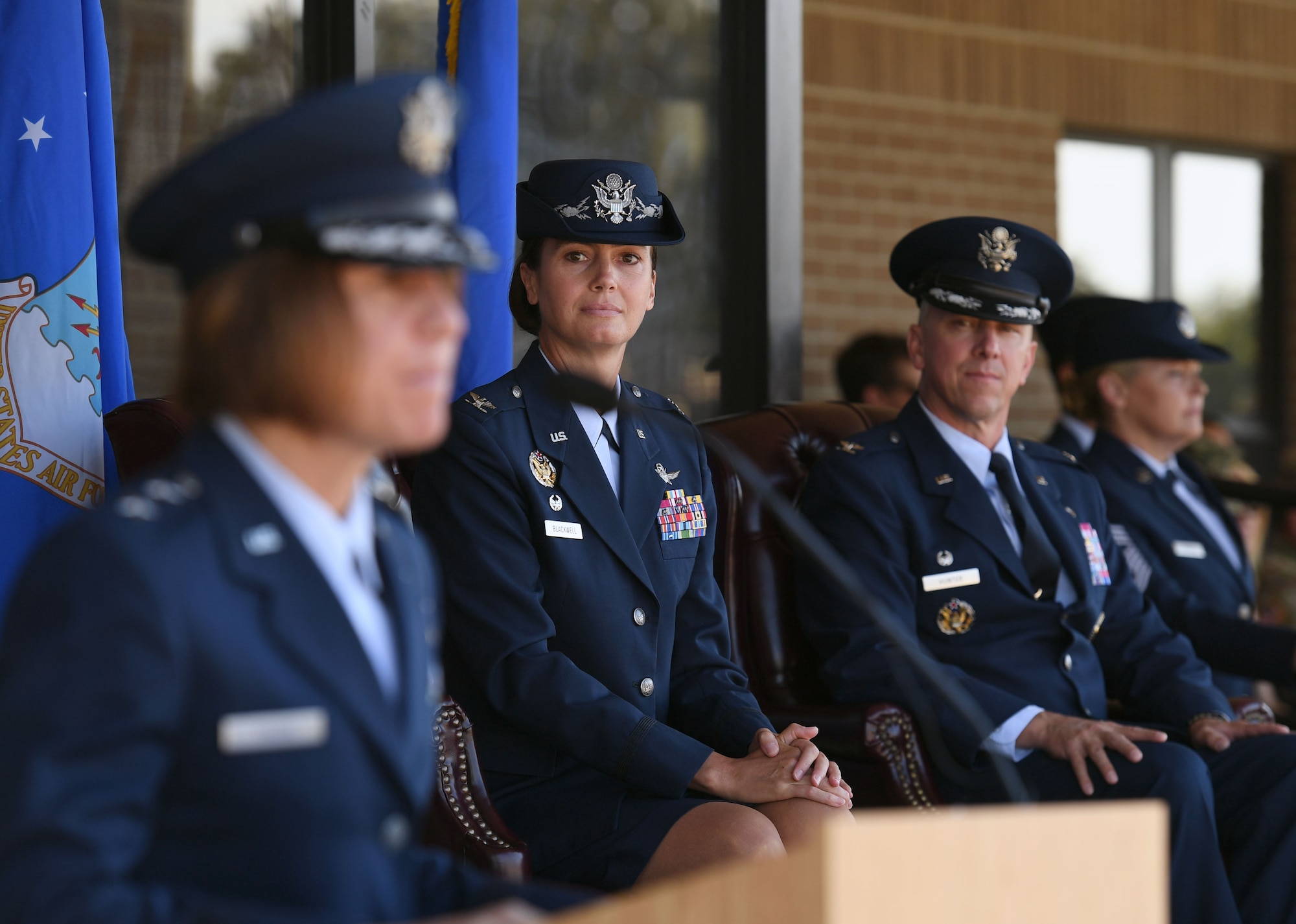 U.S. Air Force Col. Heather Blackwell, outgoing 81st Training Wing commander, and Col. William Hunter, incoming 81st TRW commander, looks on as Maj. Gen. Andrea Tullos, Second Air Force commander, delivers remarks during the change of command ceremony on the Levitow Training Support Facility drill pad at Keesler Air Force Base, Mississippi, June 17, 2021. The ceremony is a symbol of command being exchanged from one commander to the next by the handing-off of a ceremonial guidon. Blackwell is now assigned to the Air Combat Command. (U.S. Air Force photo by Kemberly Groue)