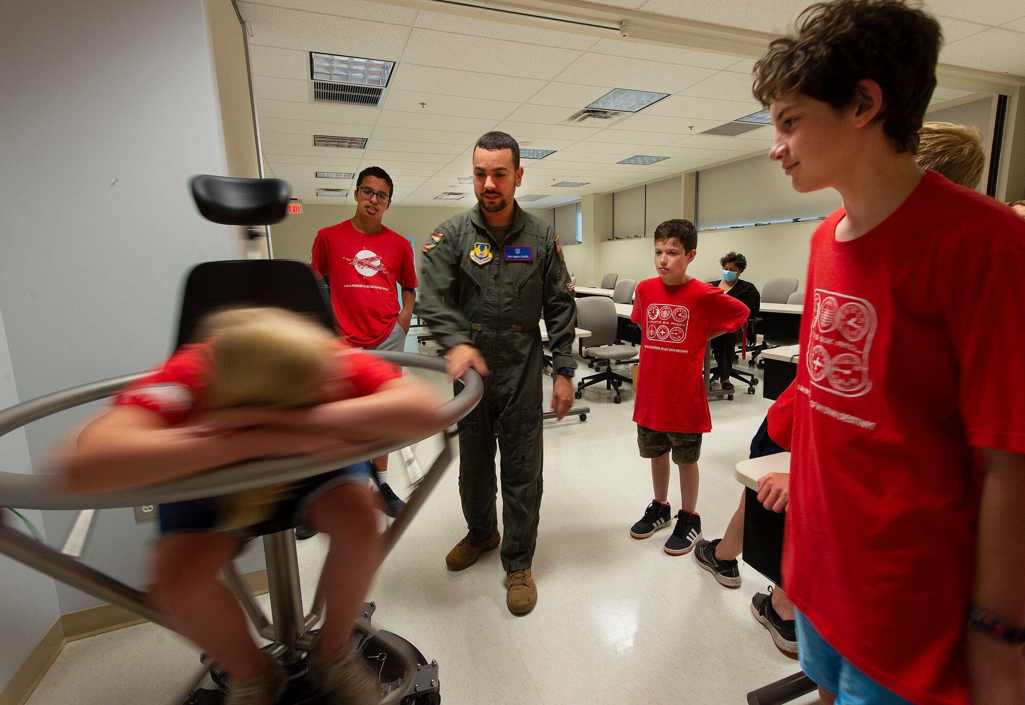 Senior Airman Fabian Cancel, U.S. School of Aerospace Medicine, spins a Space Camp participant in a Barany chair June 15, 2021, during a visit to the school on Wright-Patterson Air Force Base, Ohio. Air Camp is a STEM aviation program that is trying to raise interests in aviation amongst middle school students. (U.S. Air Force photo by R.J. Oriez)