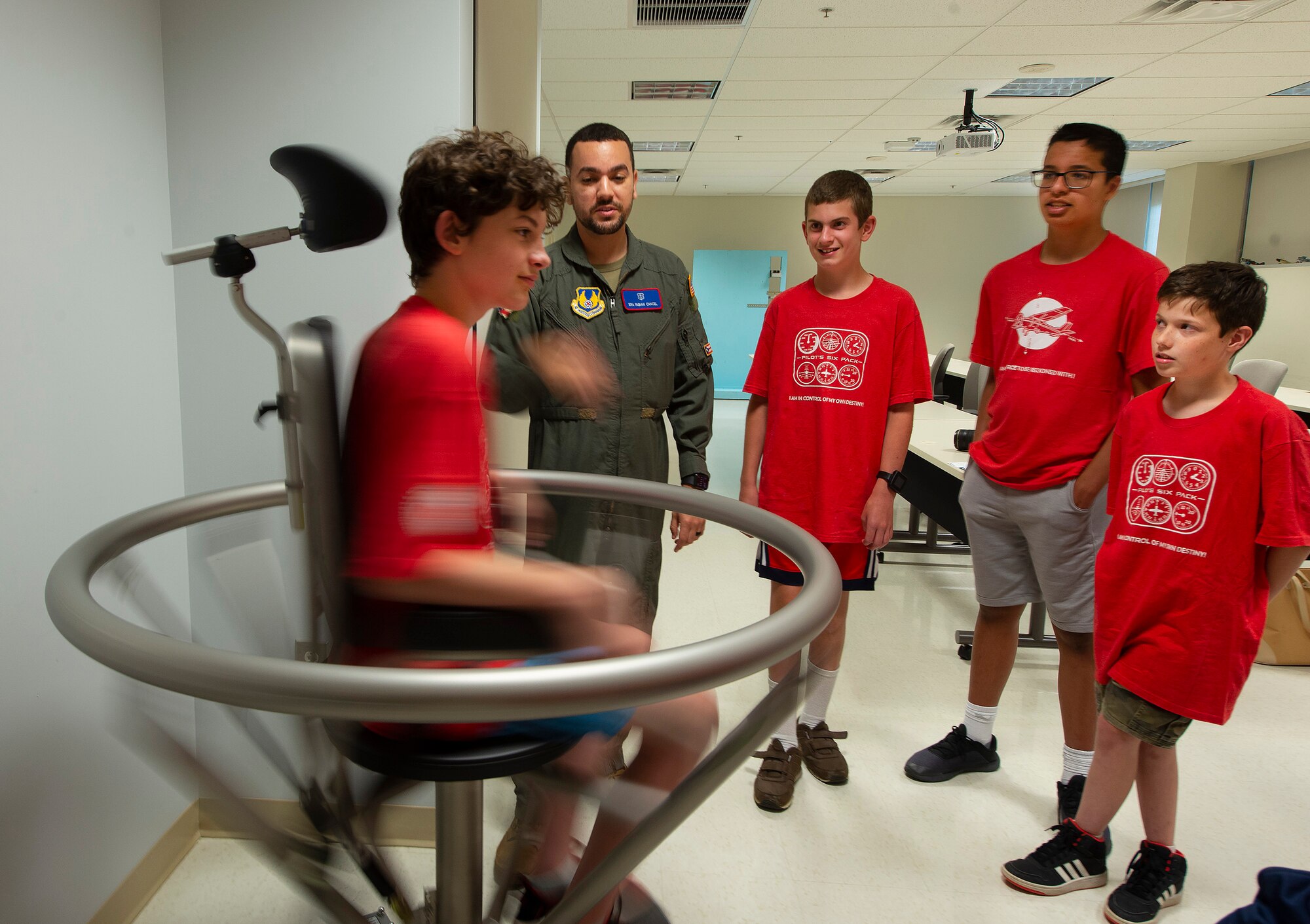 Senior Airman Fabian Cancel, U.S. School of Aerospace Medicine, spins a Space Camp participant in a Barany chair June 15, 2021, during a visit to the school on Wright-Patterson Air Force Base, Ohio. Air Camp is a STEM aviation program that is trying to raise interests in aviation amongst middle school students. (U.S. Air Force photo by R.J. Oriez)